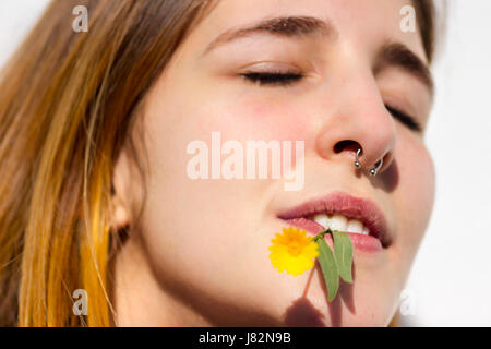 Junge Frau mit einem Nasenring und eine kleine Blume im Mund Stockfoto