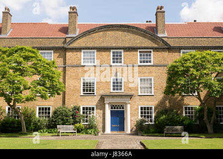 Fassade außen eines klassischen britischen georgischen Herrenhauses in Ziegel, weiße Fenster und blaue Tür gebaut. Mit Garten, Rasen und Bäumen in der front Stockfoto