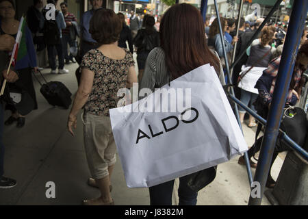 Frau zu Fuß auf der Madison Avenue mit ein Aldo Designer Shopping-Tasche über die Schulter in New York City geschleudert. Stockfoto