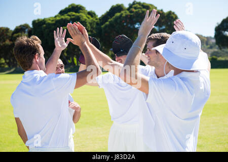 Lächelnde Cricket-Spieler feiert Sieg im Feld gegen klaren Himmel Stockfoto