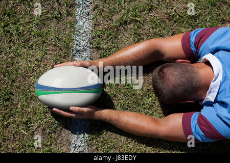 Rückansicht des Rugby-Spieler mit Ball auf der Torlinie am Spielfeld Stockfoto