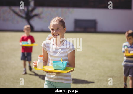 Glücklich Schulmädchen halten Mahlzeit im Fach in der Schule Stockfoto