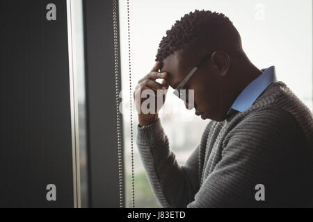 Spannte executive Stand in der Nähe der Fenster im Büro Stockfoto