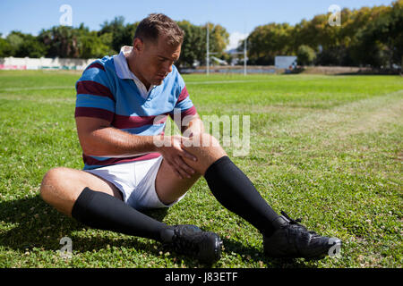 Volle Länge des Rugby-Spieler sitzen auf Spielfeld an sonnigen Tag Stockfoto