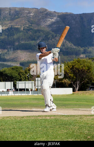 Gesamte Länge der Schlagmann spielen Cricket auf Feld an sonnigen Tag Stockfoto