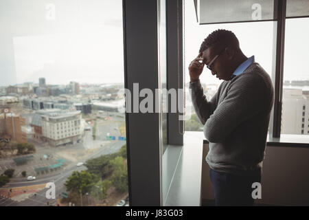 Spannte executive Stand in der Nähe der Fenster im Büro Stockfoto