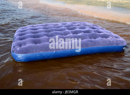 Blaue Luftmatratze im Teich schwimmen. Eine aufblasbare Matratze am Strand. Stockfoto