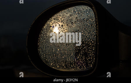 Die Reflexion der Sonne in ein Glas gefüllt mit Tropfen Regenwasser, das Auto Form reflektiert die Sonne, das Glas eine Menge von Wassertropfen Stockfoto