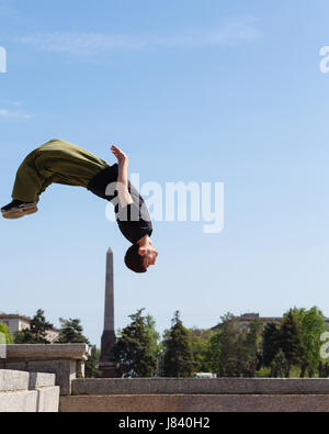 Junger Mann tut einen Back Flip im Hintergrund Obelisk. Parkour im urbanen Raum. Sport in der Stadt. Sportliche Aktivität. Stockfoto