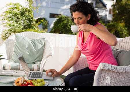 Frau trinkt Kaffee während mit Laptop am Tisch im café Stockfoto