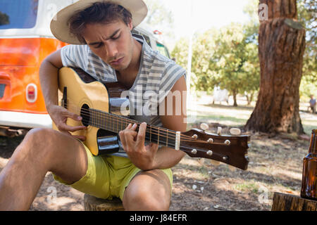 Junger Mann spielt Gitarre im park Stockfoto