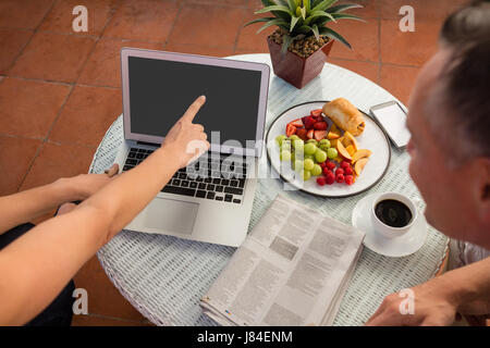 Erhöhte Ansicht von Mann und Frau diskutieren über Laptop auf Balkon Stockfoto