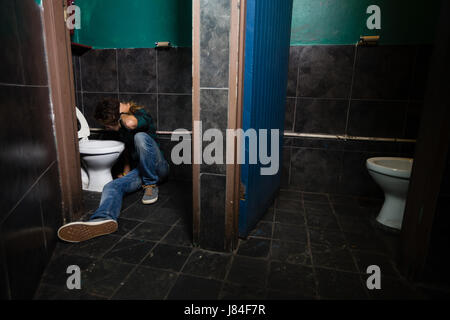 Mann, Erbrechen am Toilettenbecken im Waschraum Stockfoto