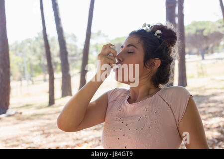 Junge Frau mit Asthma-Inhalator im park Stockfoto