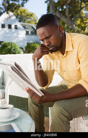 Ernste Jüngling, Zeitung lesen, während Sie vom Tisch im Café sitzen Stockfoto