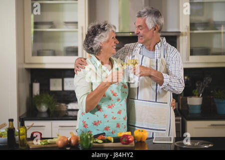 Älteres paar Weingläser stehen gemeinsam in der Küche zu Hause Toasten lächelnd Stockfoto