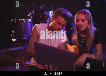 Junge männliche und weibliche Musiker mit Laptop beim üben im Nachtclub Stockfoto