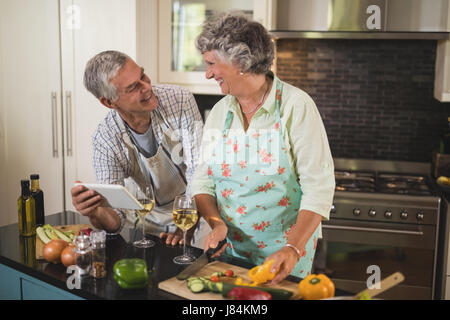 Lächelnd älteres paar sahen einander stehend in der Küche zu Hause Stockfoto