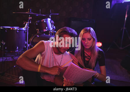 Junge männliche und weibliche Musiker üben mit Notenblätter in Nachtclub Stockfoto