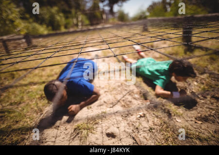 Kinder kriechen unter dem Netz während der Hindernis-Parcours mit Boot camp Stockfoto