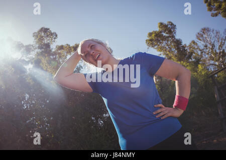 Müde Frau mit Hand auf die Hüfte in das Boot Camp an einem sonnigen Tag Stockfoto