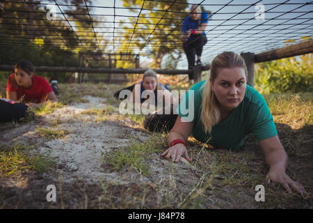 Gruppe von Fit Frauen kriechen unter dem Netz während des Trainings der Hindernis-Parcours im Boot camp Stockfoto