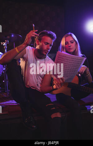 Niedrigen Winkel Ansicht der männlichen und weiblichen Musiker üben mit Notenblätter in Nachtclub Stockfoto