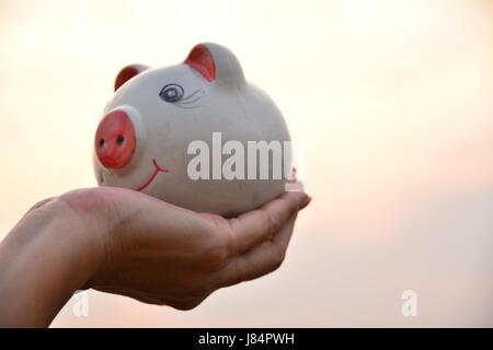 Hand mit Sparschwein Idee Konzept unter freiem Himmel Stockfoto