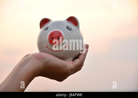 Hand mit Sparschwein Idee Konzept unter freiem Himmel Stockfoto