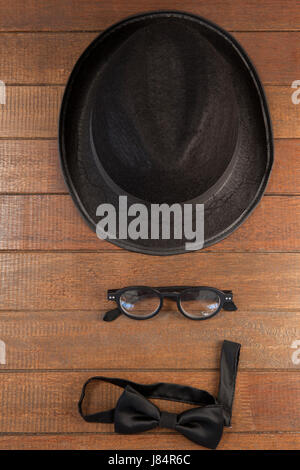 Nahaufnahme von Hut, Brille und Fliege auf hölzernen Hintergrund angeordnet Stockfoto