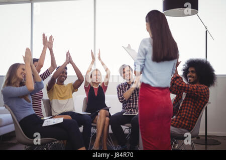 Rückansicht des Geschäftsfrau stehend mit Jubel für ihr Büro-team Stockfoto