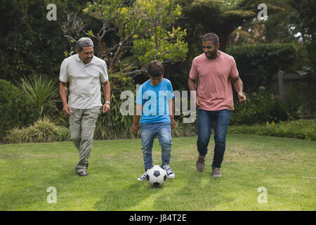 Generationsübergreifende Familienglück gemeinsam Fußball zu spielen, auf Feld im park Stockfoto