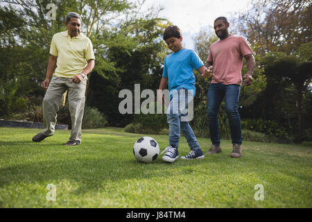 Lächeln mehr-Generationen-Familie zusammen mit Fußball auf Feld im Park zu spielen Stockfoto