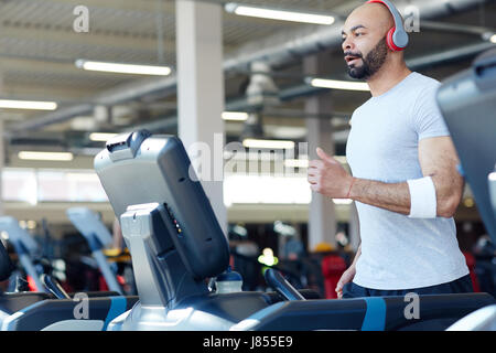 Aktive junge Mann läuft auf Laufband Stockfoto