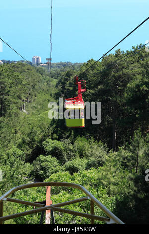 Gelbe Seilbahn vom Berg zum Meer über Wald bewegt Stockfoto