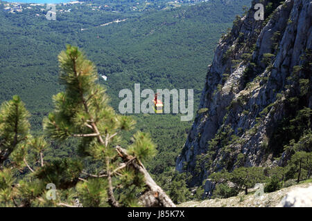 Gelbe Seilbahn auf Hintergrund mit sehr hohen Berg und Meer Stockfoto