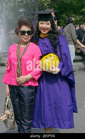 Eine chinesische Gaststudent feiern ihr Abitur am NYU mit einer Frau, die zu ihrer Mutter zu sein scheint. Im Washington Square Park in New York City Stockfoto