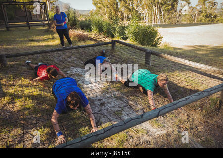 Gruppe von Fit Frauen kriechen unter dem Netz während des Trainings der Hindernis-Parcours im Boot camp Stockfoto