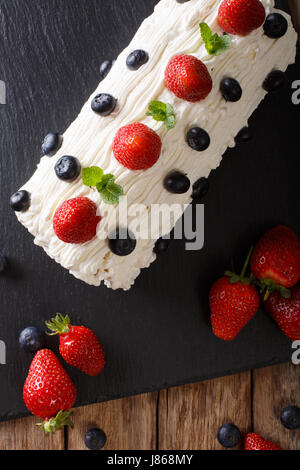 Weihnachten-Erdbeere Rollen mit geschlagener Sahne, Minze und Heidelbeeren Nahaufnahme auf dem Tisch. Vertikale Ansicht von oben Stockfoto