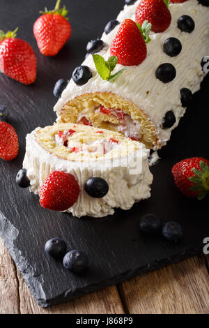 Delicious geschnitten Erdbeerkuchen mit geschlagener Sahne, Minze und Heidelbeeren Nahaufnahme auf dem Tisch. vertikale Stockfoto