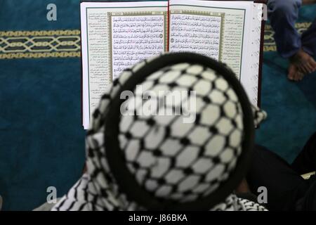 Gaza-Stadt, Gazastreifen, Palästinensische Gebiete. 27. Mai 2017. Ein palästinensischer Mann liest eine Kopie des Koran, Islam heiligste Buch, am ersten Tag des Fastens in den Heiligen Fastenmonat Ramadan, in der al-Omari-Moschee in Gaza-Stadt, am 27. Mai 2017. Ramadan ist für Muslime heilig, weil es in diesem Monat ist die Tradition besagt, dass der Prophet Mohammed der Koran offenbart wurde. Das Fasten ist eine der fünf wichtigsten religiösen Pflichten unter dem Islam. Mehr als 1. Stockfoto