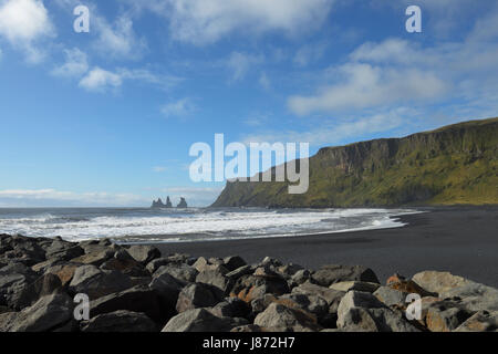 Schwarze Lavastrand mit Basalt-Stacks von Reynisdrangar im Hintergrund, Vik, Vestur-Skaftafellssysla, Island Stockfoto