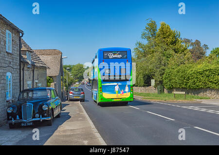 Nummer 40 Purbeck Breezer Double Decker Bus entlang der Straße durch Corfe Castle Village reisen, Dorset im Mai - 1958 Wolseley 6/90 geparkt Stockfoto