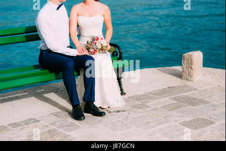 Brautpaar auf der Bank. Nahaufnahme der Beine. Hochzeit in Montenegro. Stockfoto