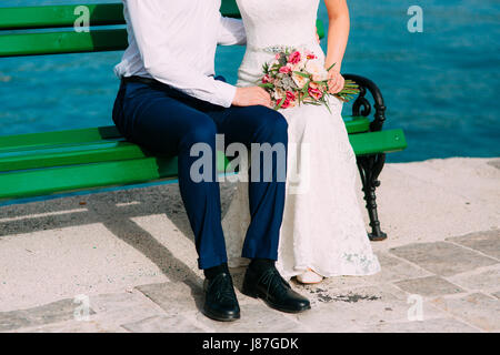 Brautpaar auf der Bank. Nahaufnahme der Beine. Hochzeit in Montenegro. Stockfoto