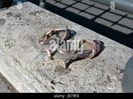 Ein paar gebrauchte Damenschuhe auf eine Betonwand in der Nähe der Donau in Budapest, Ungarn. Stockfoto