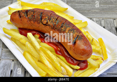 Bratwurst mit Bratkartoffeln und Ketchup auf Pappteller Französisch, Nahaufnahme, Makro, full-frame Stockfoto