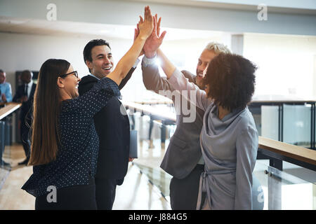 Lächelnd Schwarz und Weiß business Leute stehen in Büro- und hohe fünf während Teambuilding. Stockfoto