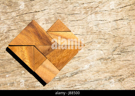 Tangram-Puzzle in Herzform auf hölzernen Hintergrund Stockfoto