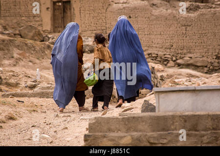 Mädchen und Frauen in Burkas zu Fuß durch einen Friedhof in der Nähe von Kabul, Afghanistan Stockfoto